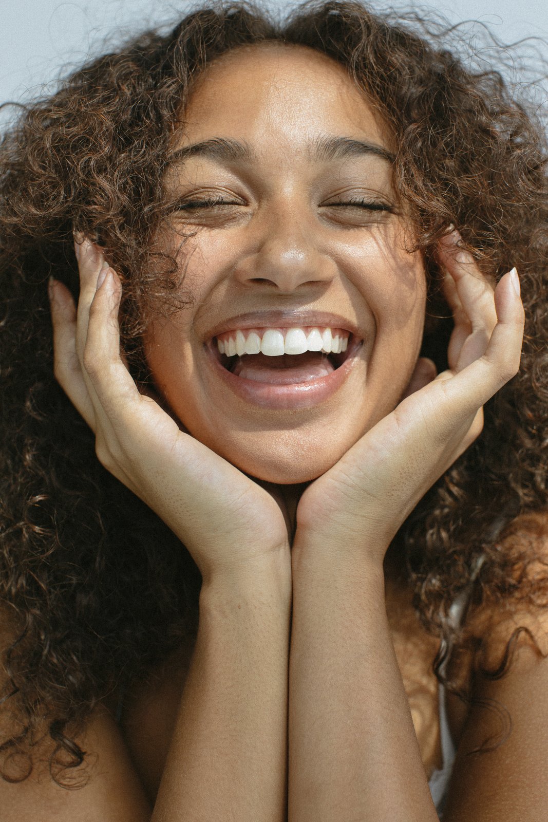 Woman laughing, hands framing her face